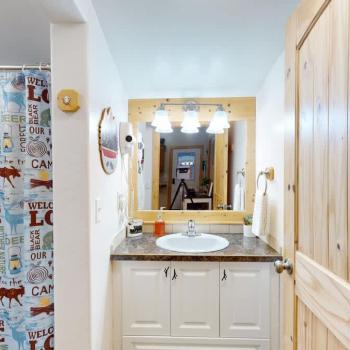 The bathroom has a sink vanity, shower tub combo, and a toilet.