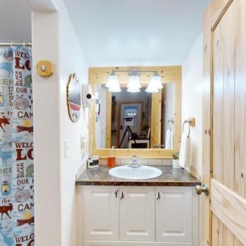 The bathroom has a sink vanity, shower tub combo, and a toilet.