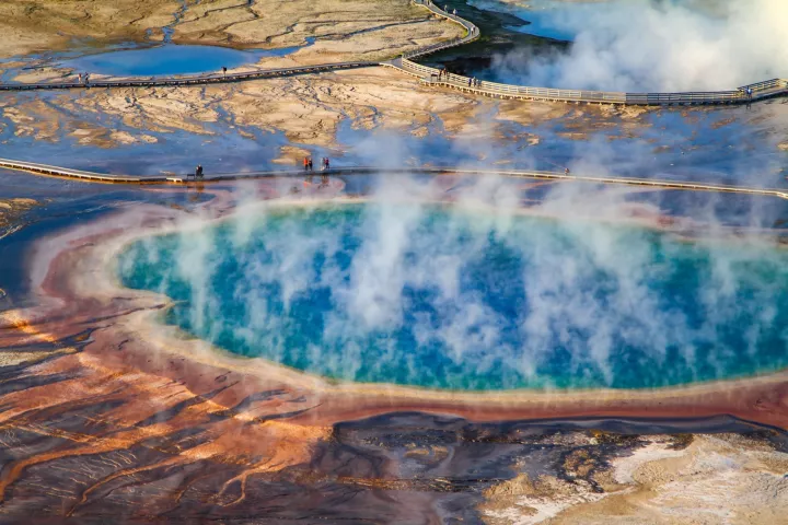 Grand Prismatic Spring from above, steam drifting over its blue center and orange rings