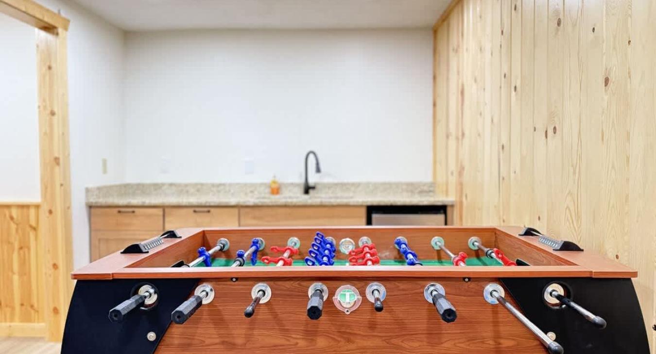 Game area downstairs in the basement with mini fridge and sink.