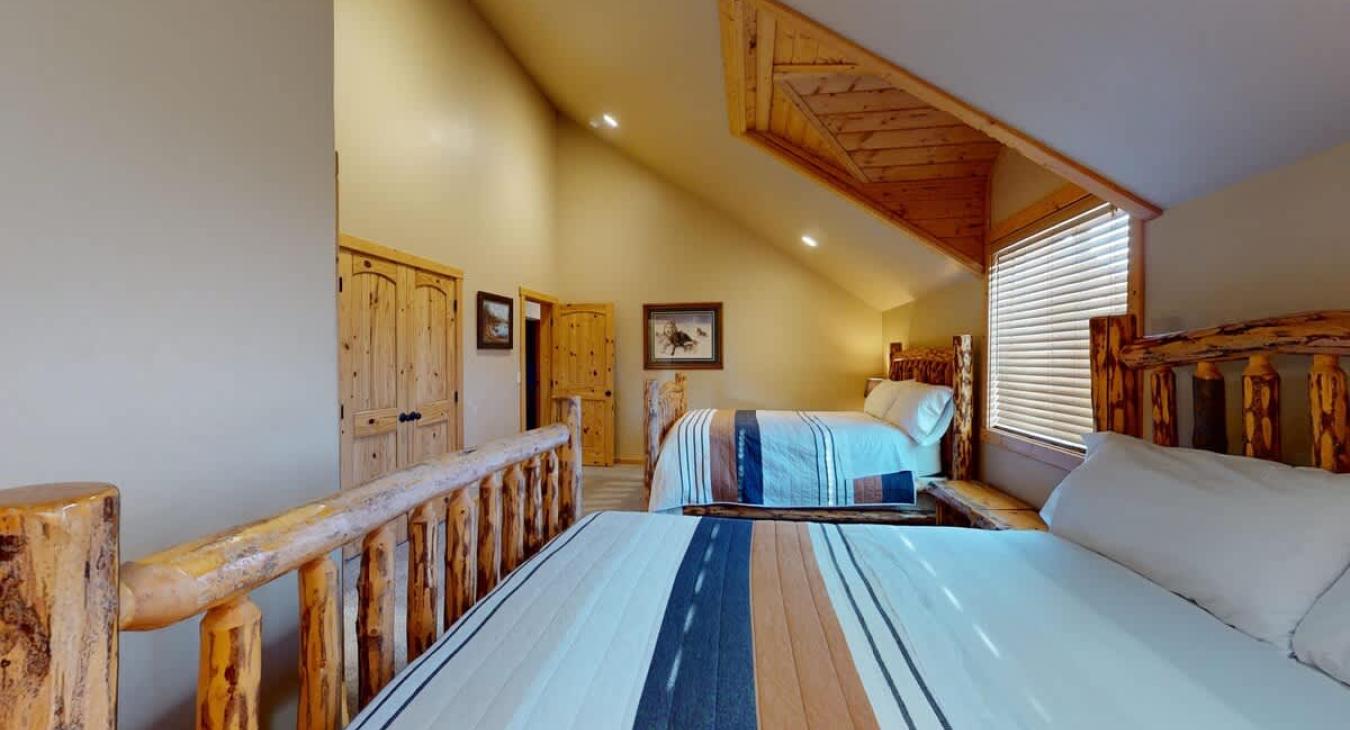 A large window sits between the beds, letting in natural light during the day and offering peaceful views of towering pines or drifting snow, depending on the season.