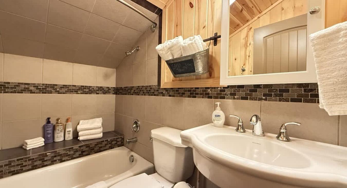 Upstairs bathroom with shower/tub, toilet, and sink. Fresh clean towels are provided.
