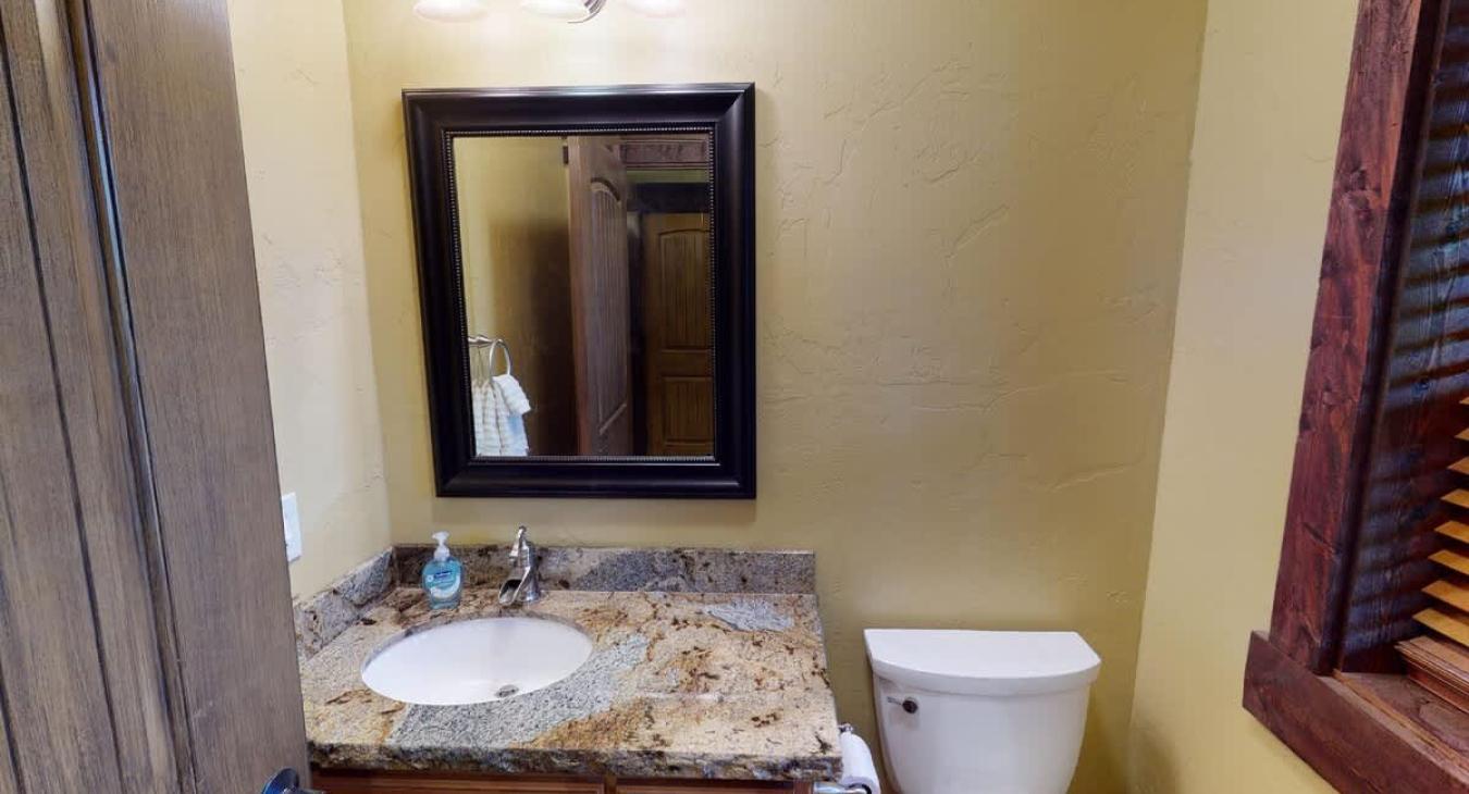 Main level half bathroom with a toilet and sink.