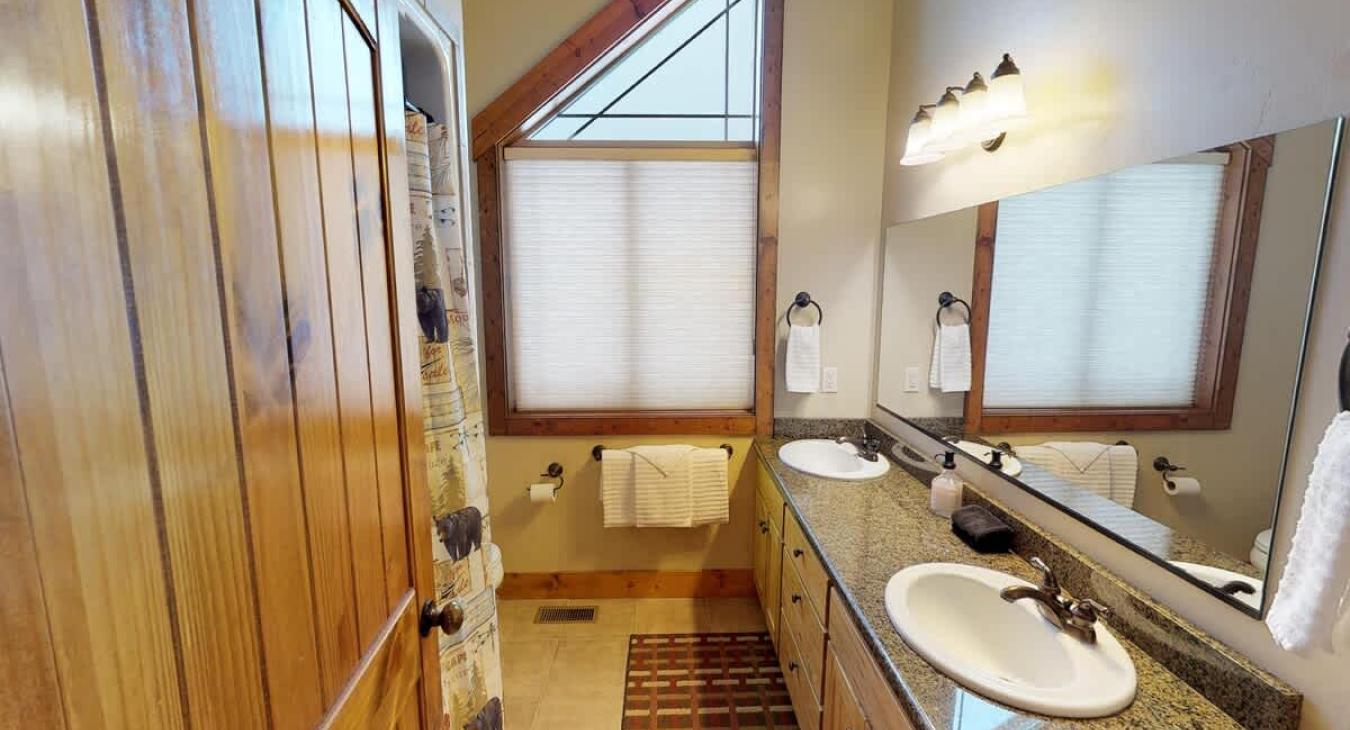 The other bathroom in the main house has a double sink vanity, a standing shower, and toilet. This bathroom is shared between two separate rooms.