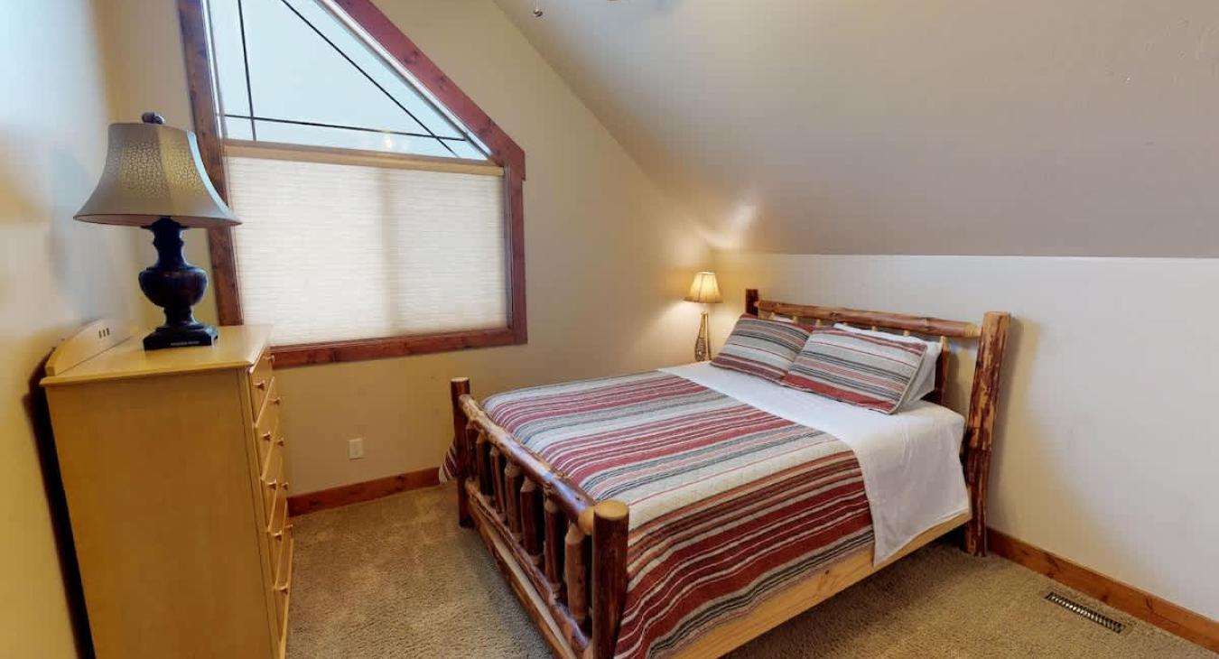 The second bedroom features a queen size bed and a large window to let natural light in.