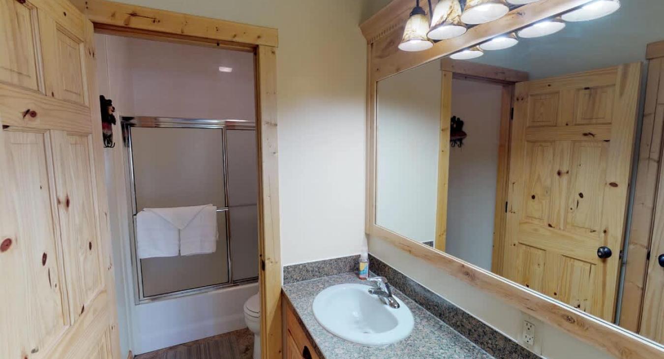 Shared bathroom located in the basement with a shower tub combo, toilet, and sink vanity.