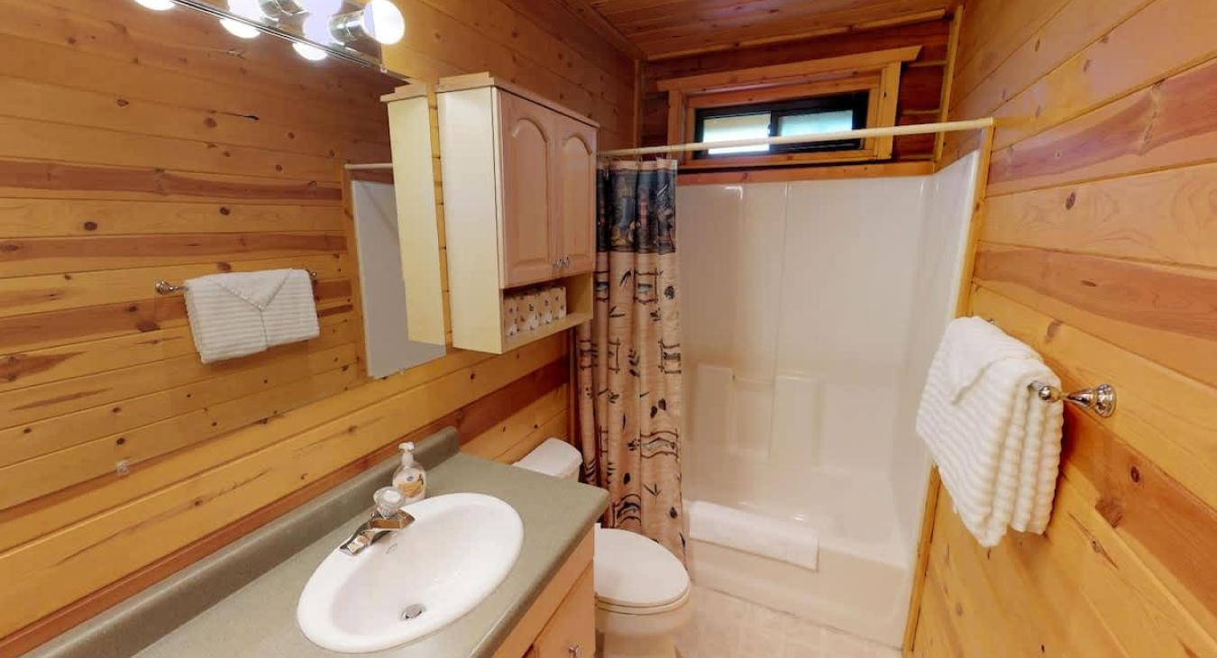 Upstairs shared bathroom with shower tub combo, toilet, and double sink vanity.