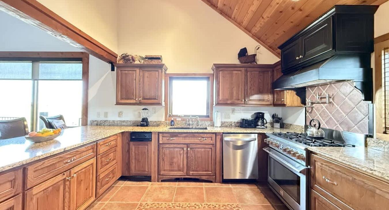 Large kitchen equipped with stainless steel appliances, pots and pans, dishes, utensils, and cooking essentials.