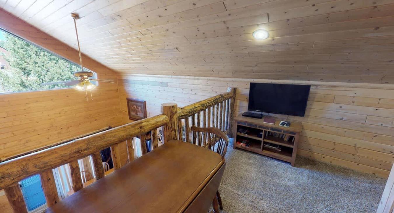Upstairs loft with an entertainment center with a tv.