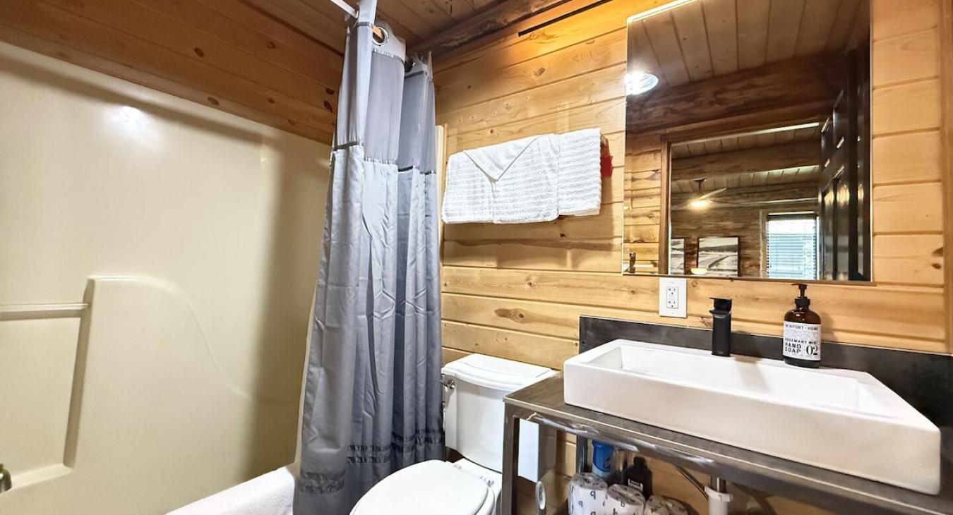 In the ensuite bathroom there is a large vanity, toilet, and a shower tub combo.