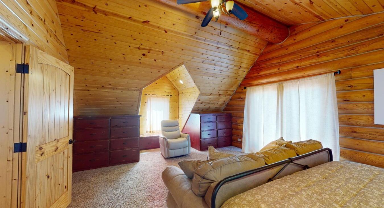This upstairs bedroom offers a cozy escape within the cabin, providing both comfort and a deep connection to the natural beauty of the surrounding area.