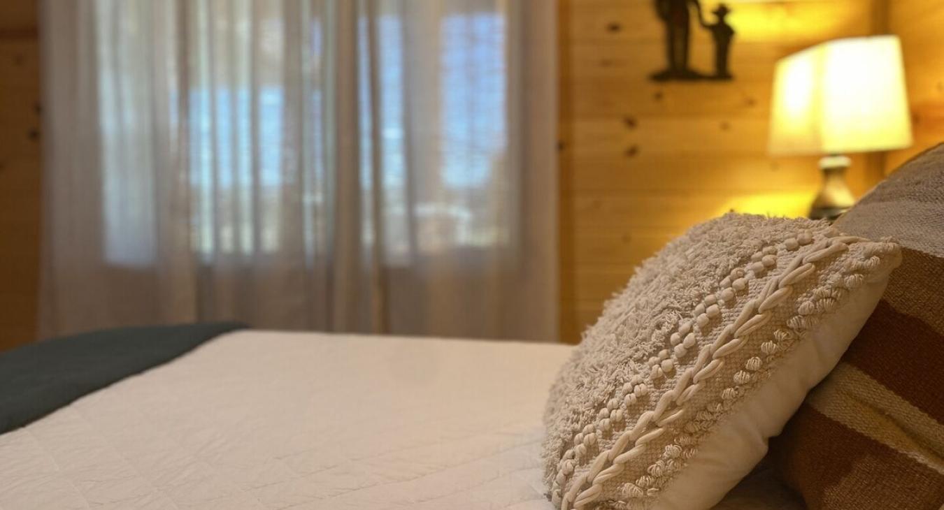 The bedroom offer a peaceful, rustic environment that blends the beauty of the cabin’s natural surroundings with the comfort and warmth needed for a relaxing stay.