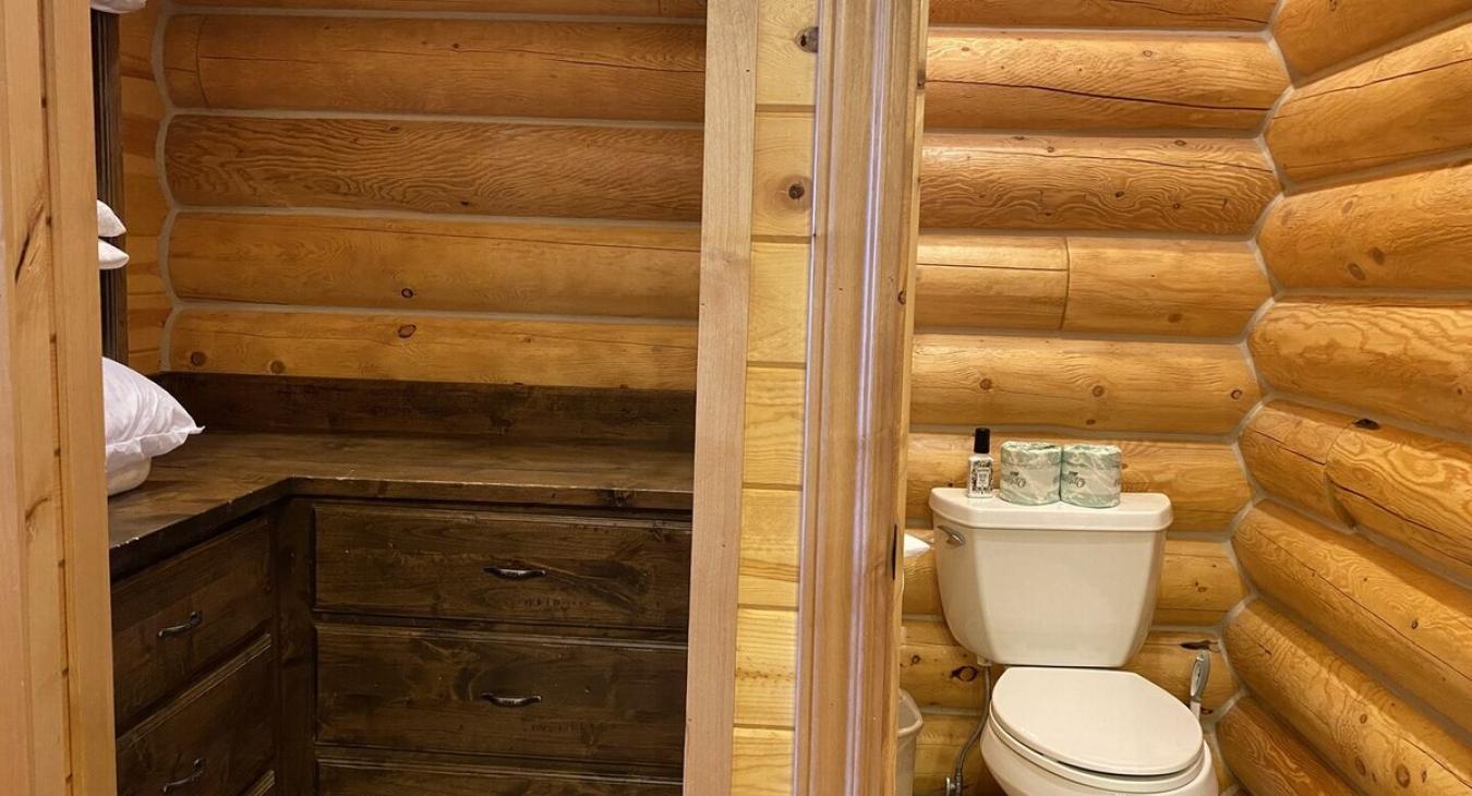 The closet is built into the wall and has shelves for extra towels and linens, as well as hanging space for coats and clothing. Its wooden shelves, hanging rods, and drawers are simple yet practical.