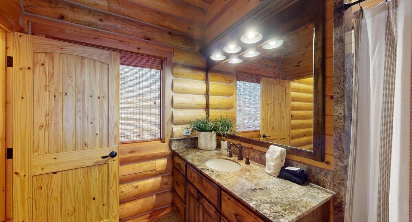The sink is simple but elegant, with a mirror above. Beneath the vanity, there are drawers and storage space for toiletries, while the countertop holds soap and makeup cloths.