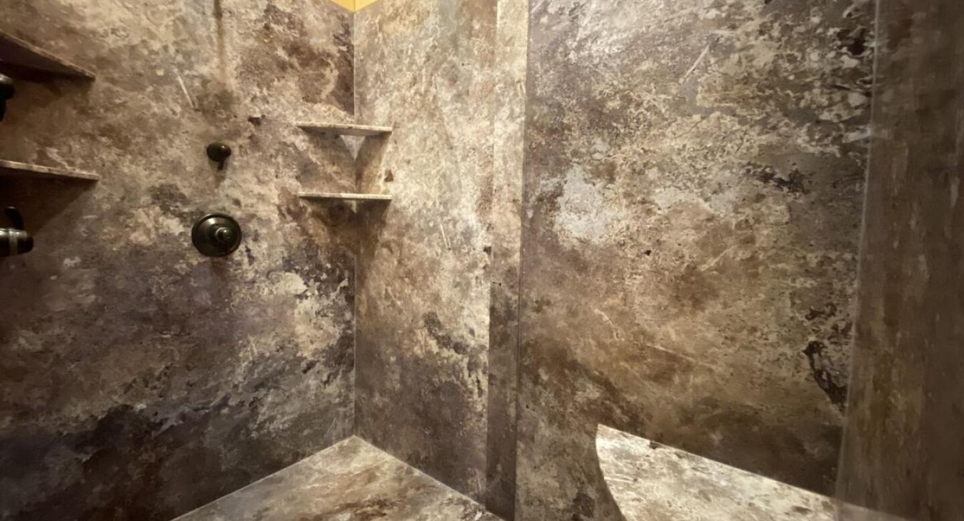 One side of the shower shelves are built into the walls, offering plenty of space for bath essentials. The walk-in shower feels like a personal retreat, where you can enjoy the natural elements around you while indulging in comfort and relaxation.
