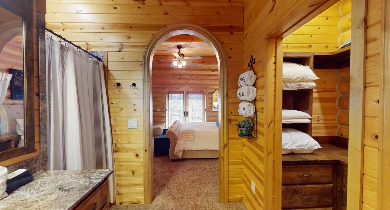As you step into the entryway of the ensuite bathroom connected to the master bedroom of the cabin, you're greeted by a charming, rustic space that blends functionality with warmth.