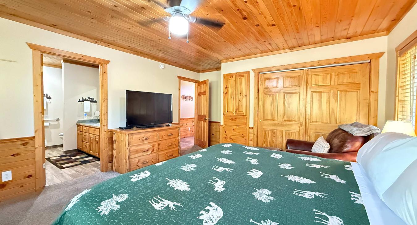 Master bedroom with a King size bed, armchair, and television.