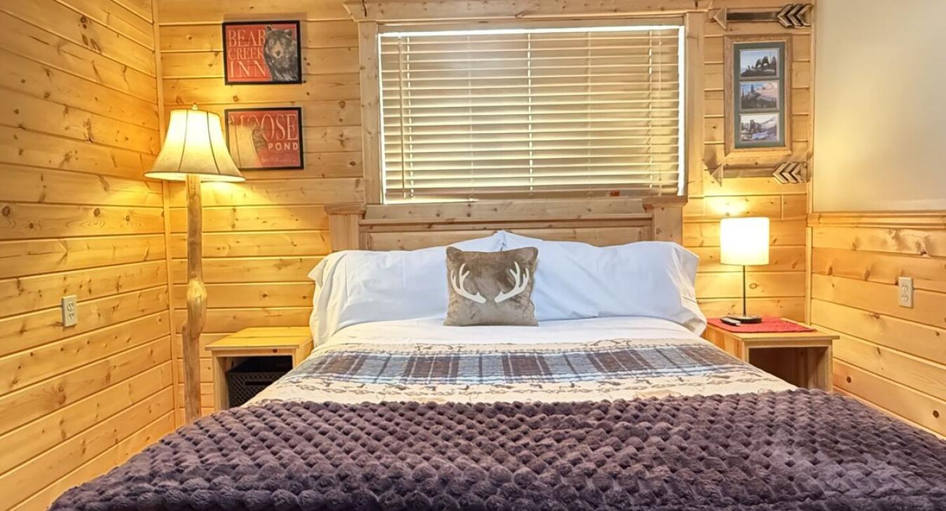 At the center of the room is a queen-sized bed with a chunky wood frame bringing that raw, rustic charm.