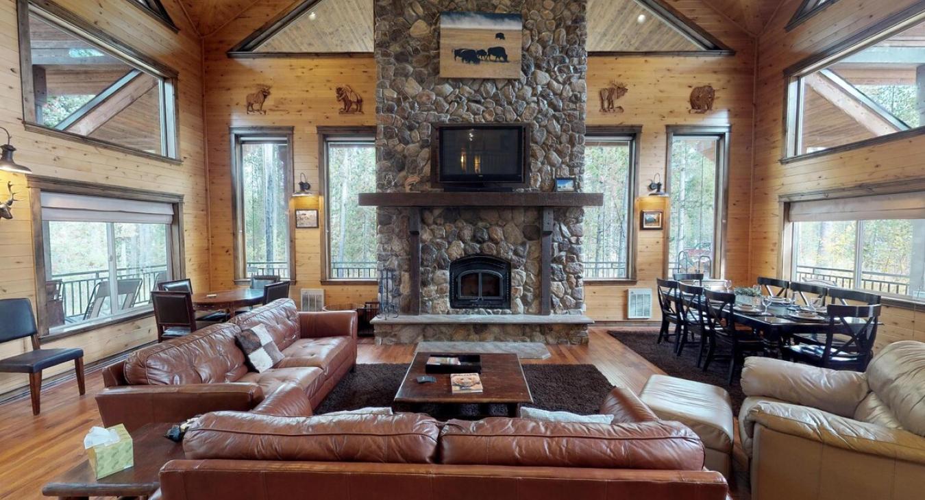 A stone fireplace nestled against a pine-paneled wall, its rough-hewn stones stacked all the way to the vaulted ceiling, with a thick wooden mantel running across the middle like a rustic crown.