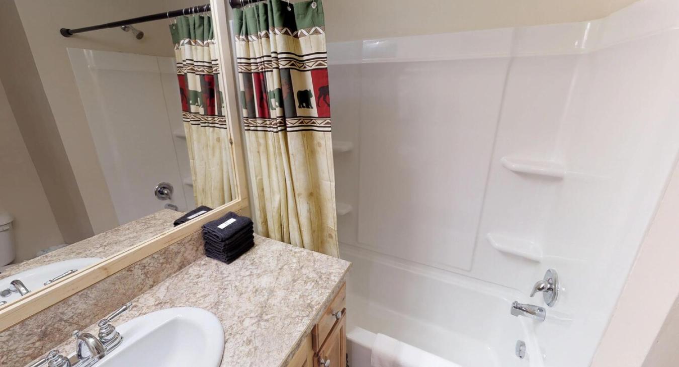 Basement shared bathroom with shower tub combo, toilet, and sink vanity.