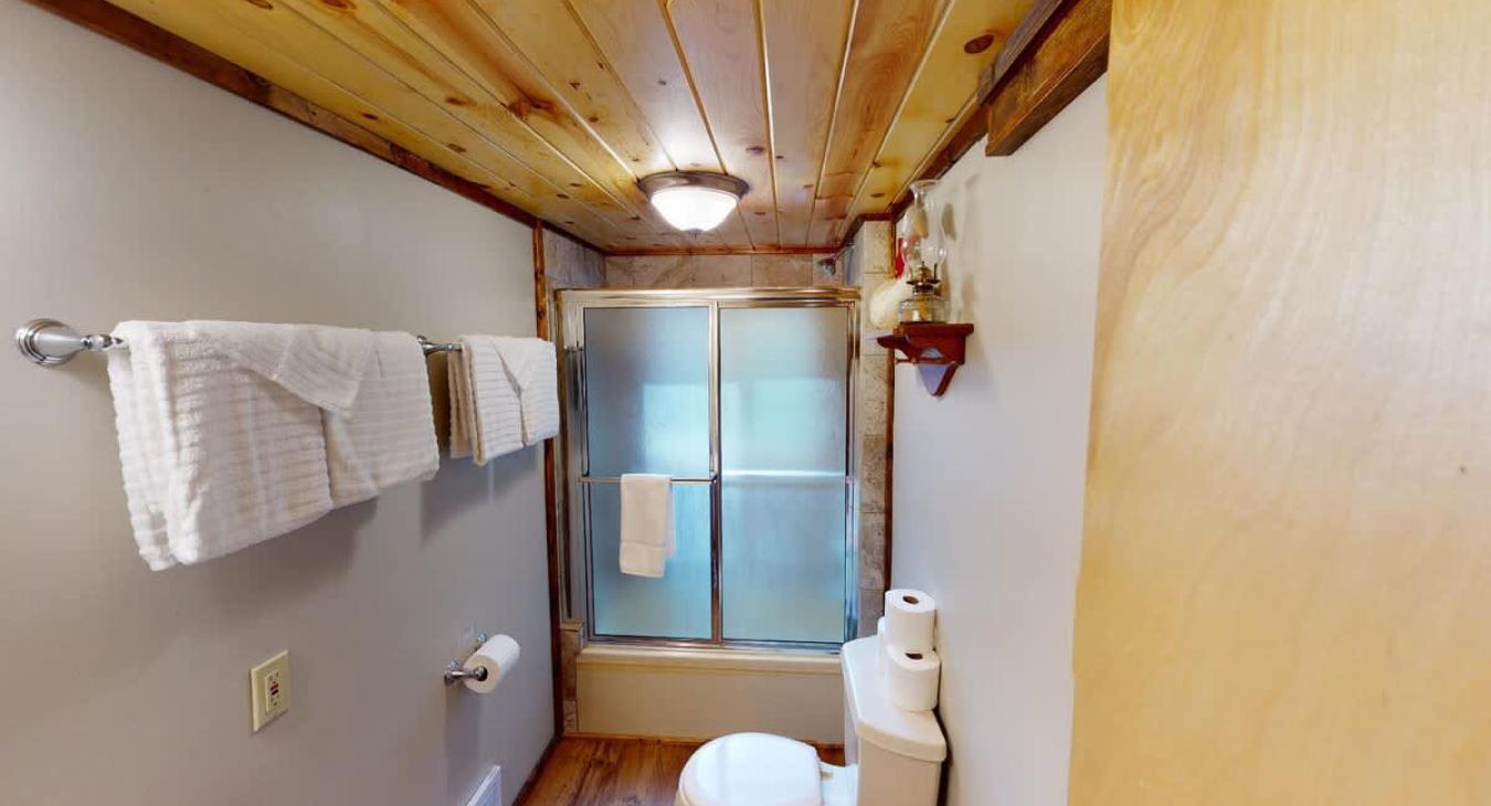 The first bedroom on the main floor is equipped with a standing shower, toilet, and a sink vanity.