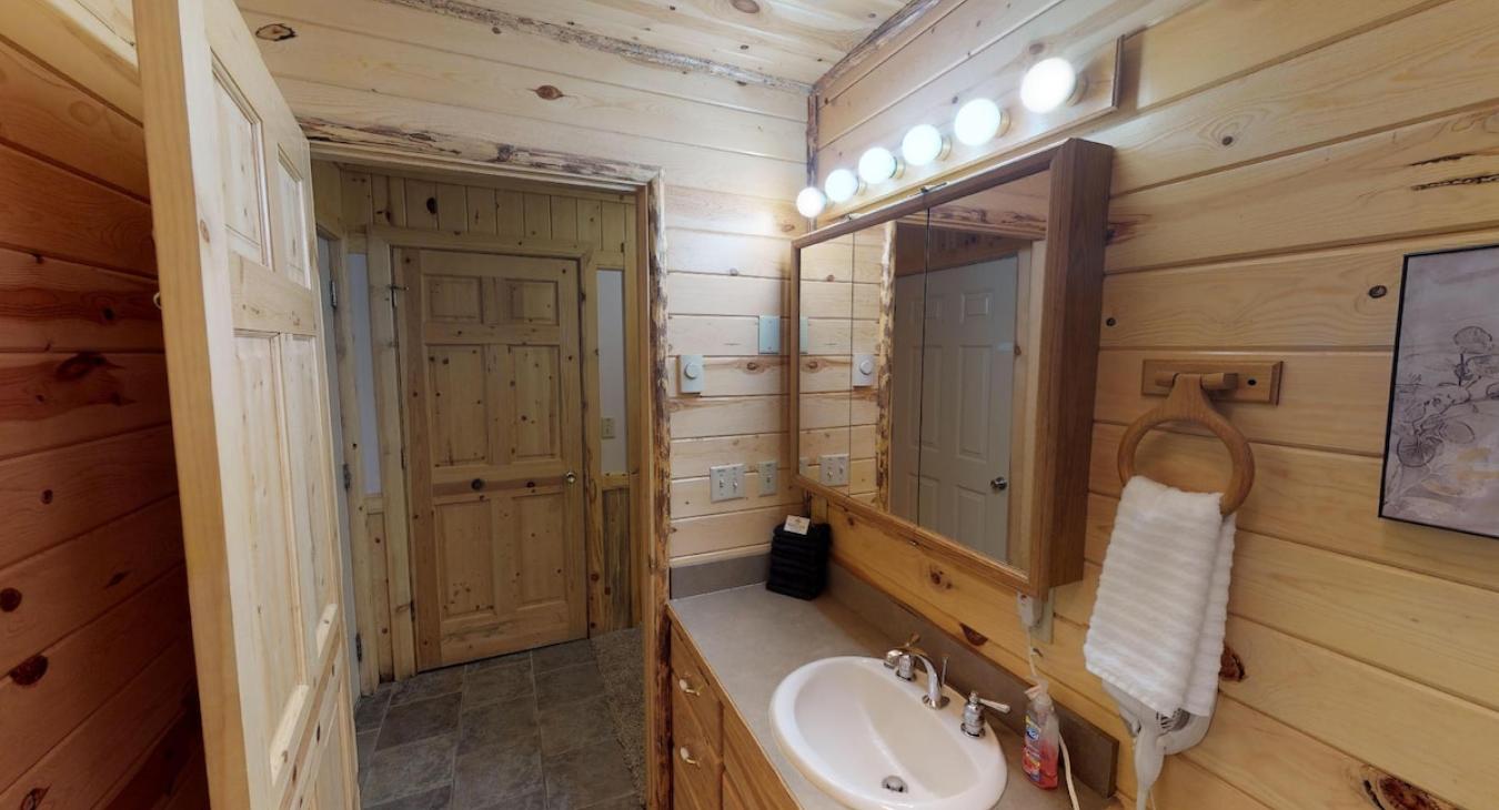 Downstairs shared bathroom with standing shower, toilet, and sink vanity.