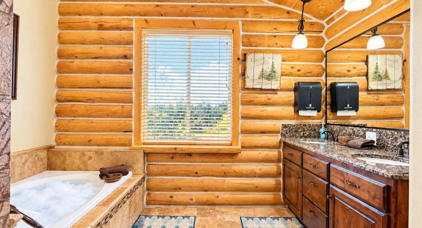 Upstairs ensuite bathroom in the bunk room with a soaking tub, standing shower, toilet, and sink vanity.