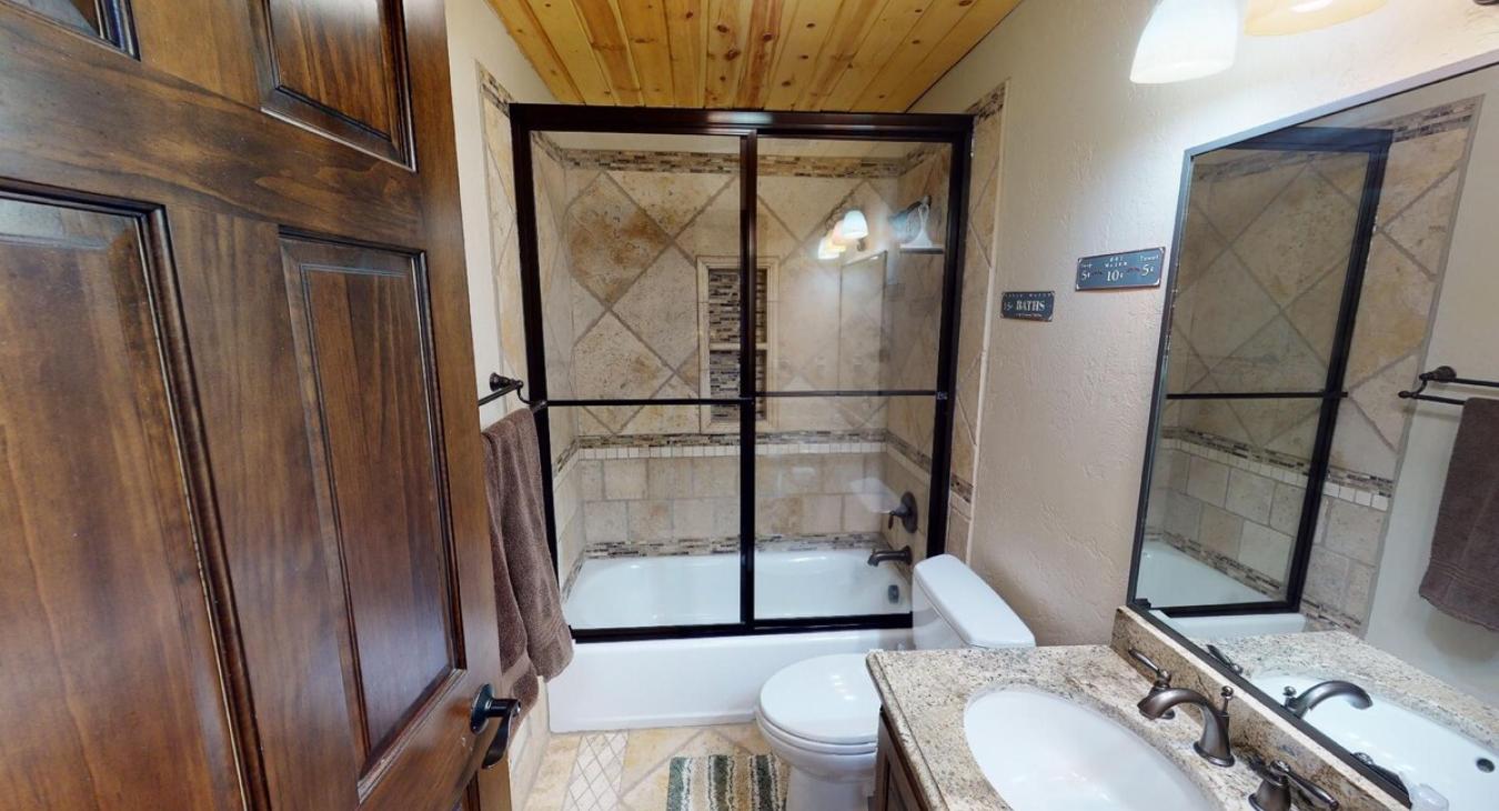 2nd bathroom downstairs with shower/tub combo, toilet, and sink vanity.