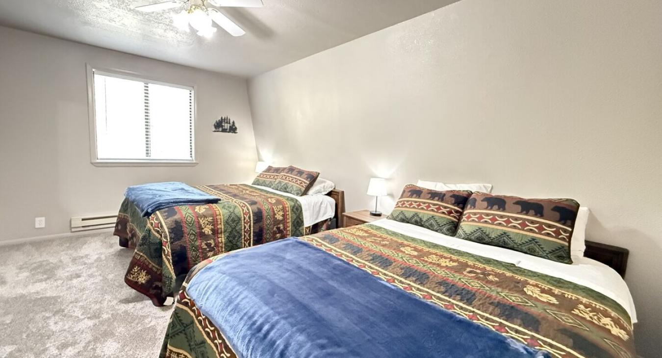 This bedroom features 2 queen beds that can comfortably fit up to 4 guests. It also has a window overlooking the outside of the cabin and a 55 inch smart tv.
