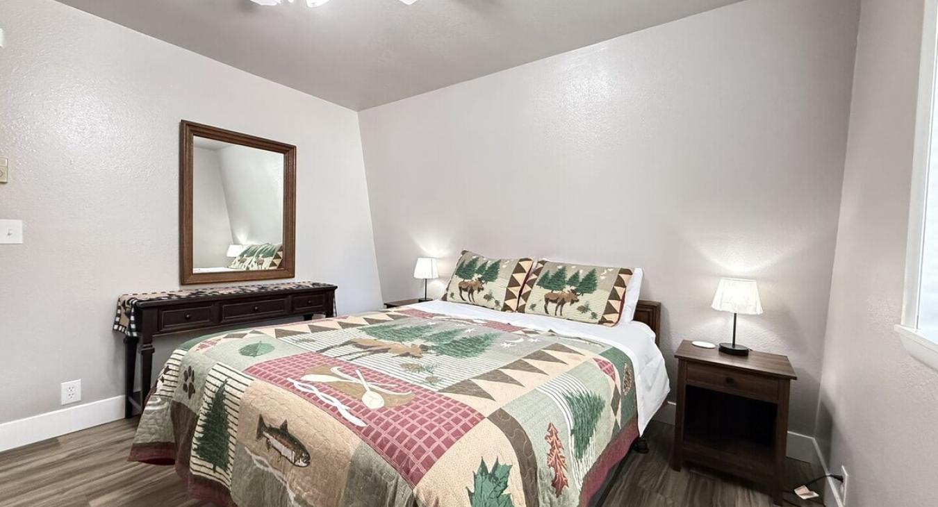 This bedroom features 1 queen bed that will comfortably sleep 2 guests with luggage racks for your bags. It also has a window overlooking the beautiful scenery of the cabin.
