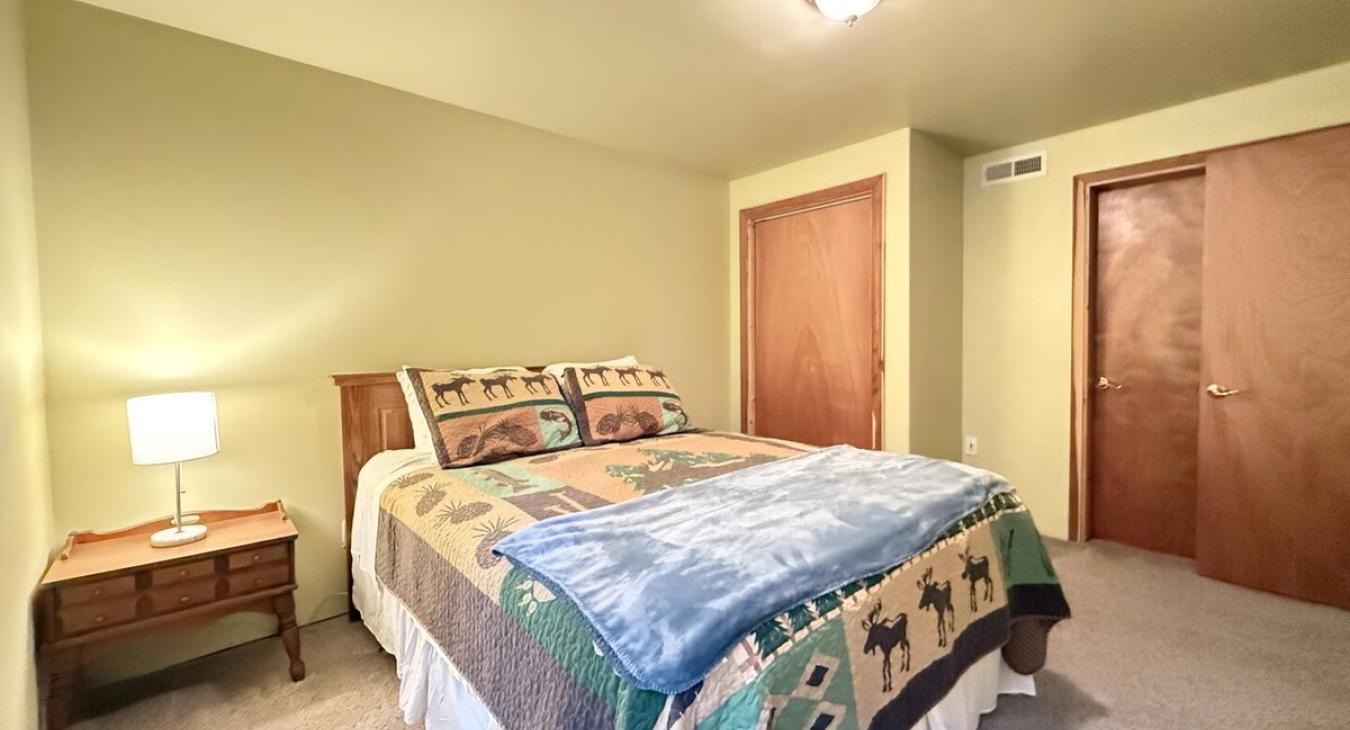 This bedroom is complete with a lamp, bedside table, and a closet to store your belongings.