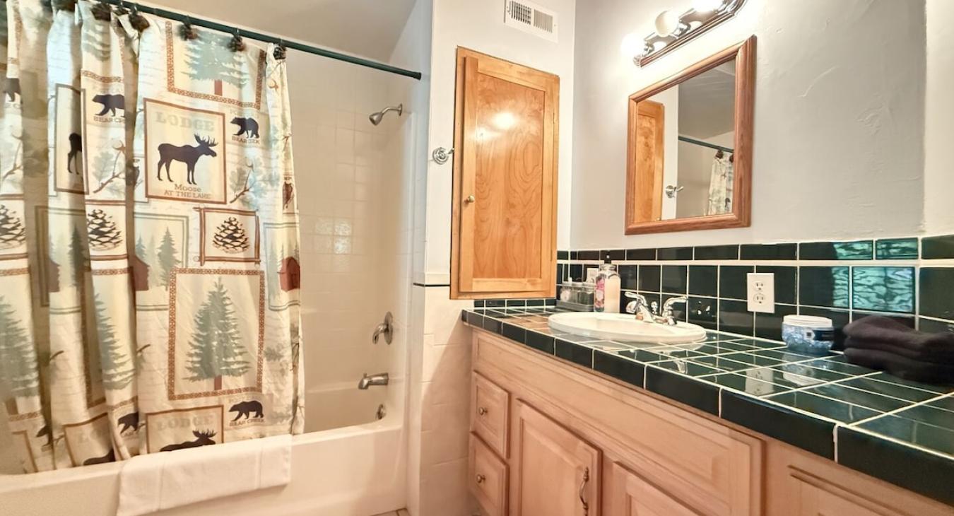 Full bathroom with shower tub combo, sink, toilet, and vanity storage. Towels are provided.