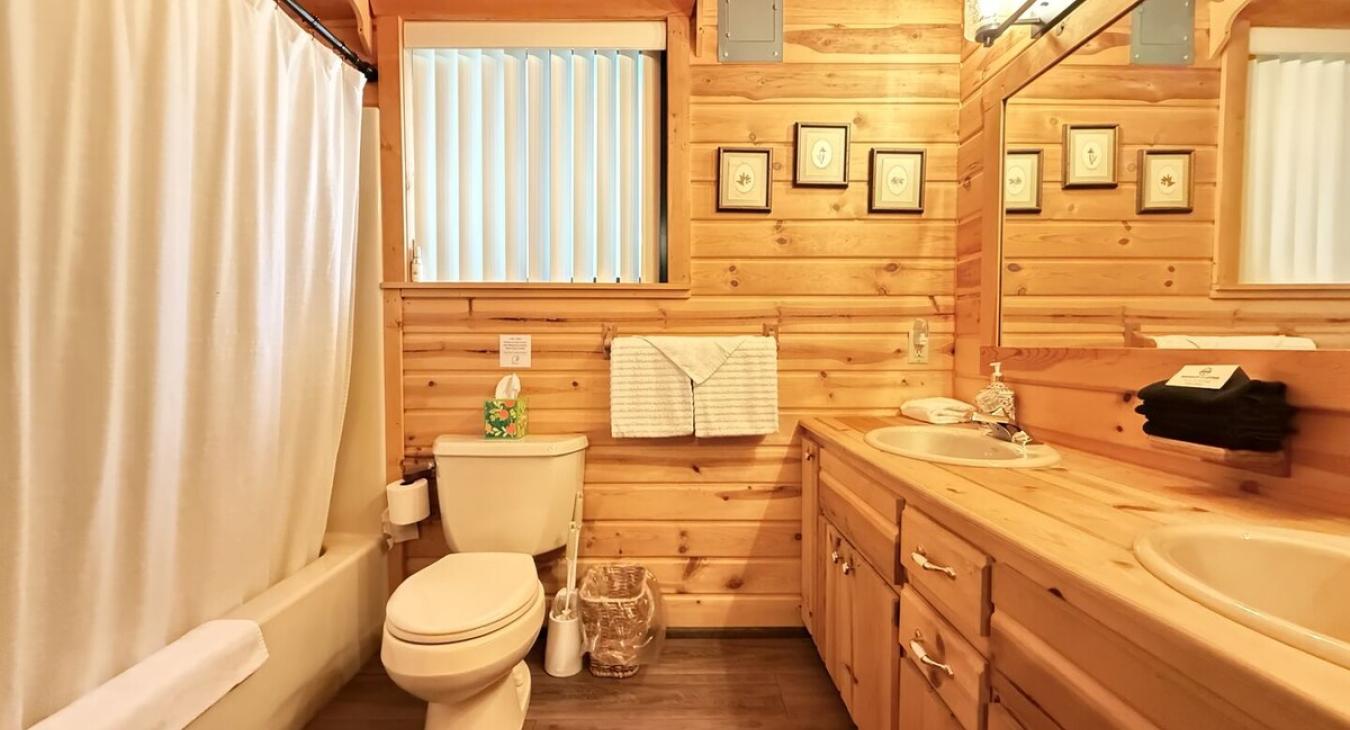 The bathroom is spacious and serene, blending the rustic elegance of the cabin with a touch of spa-like comfort.