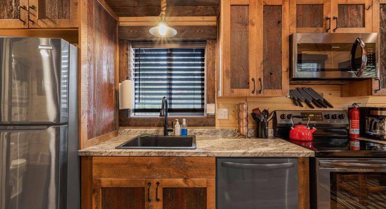 Kitchen with appliances, pots and pans, basic cooking essentials, dishes, and utensils.