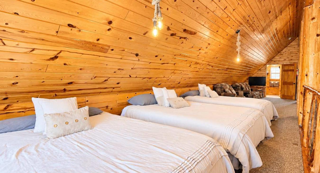 Three queen beds in the loft overlooking the living room.