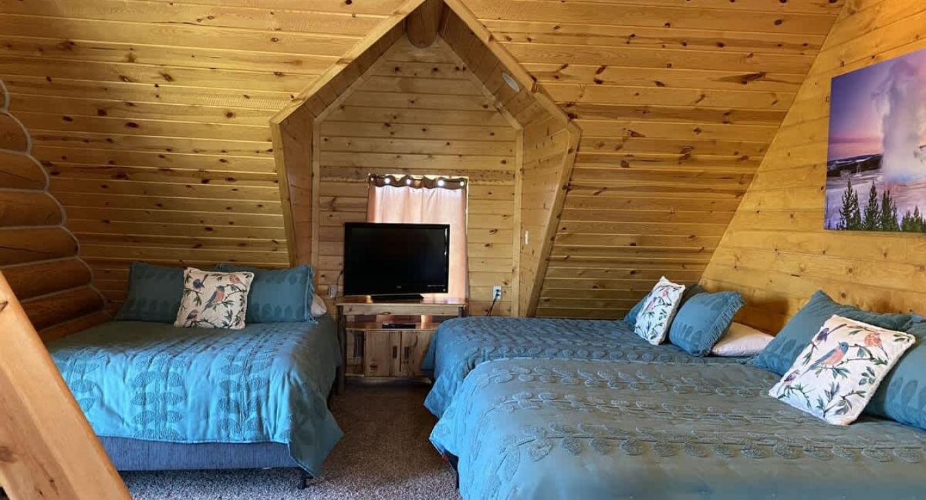 The upstairs bedroom in the cabin is a spacious, multi-functional retreat, designed to comfortably accommodate a larger group while maintaining the rustic charm of the cabin.