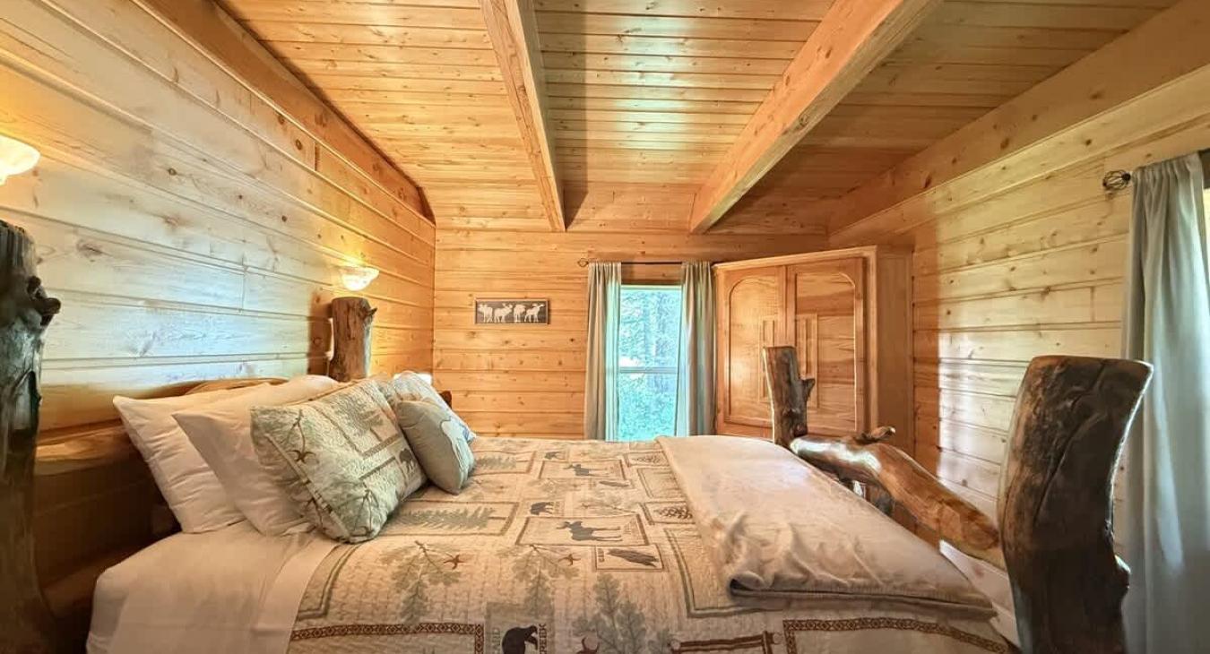 The Master bedroom is complete with two bedside tables, a lamp, and a window to enjoy your surroundings.