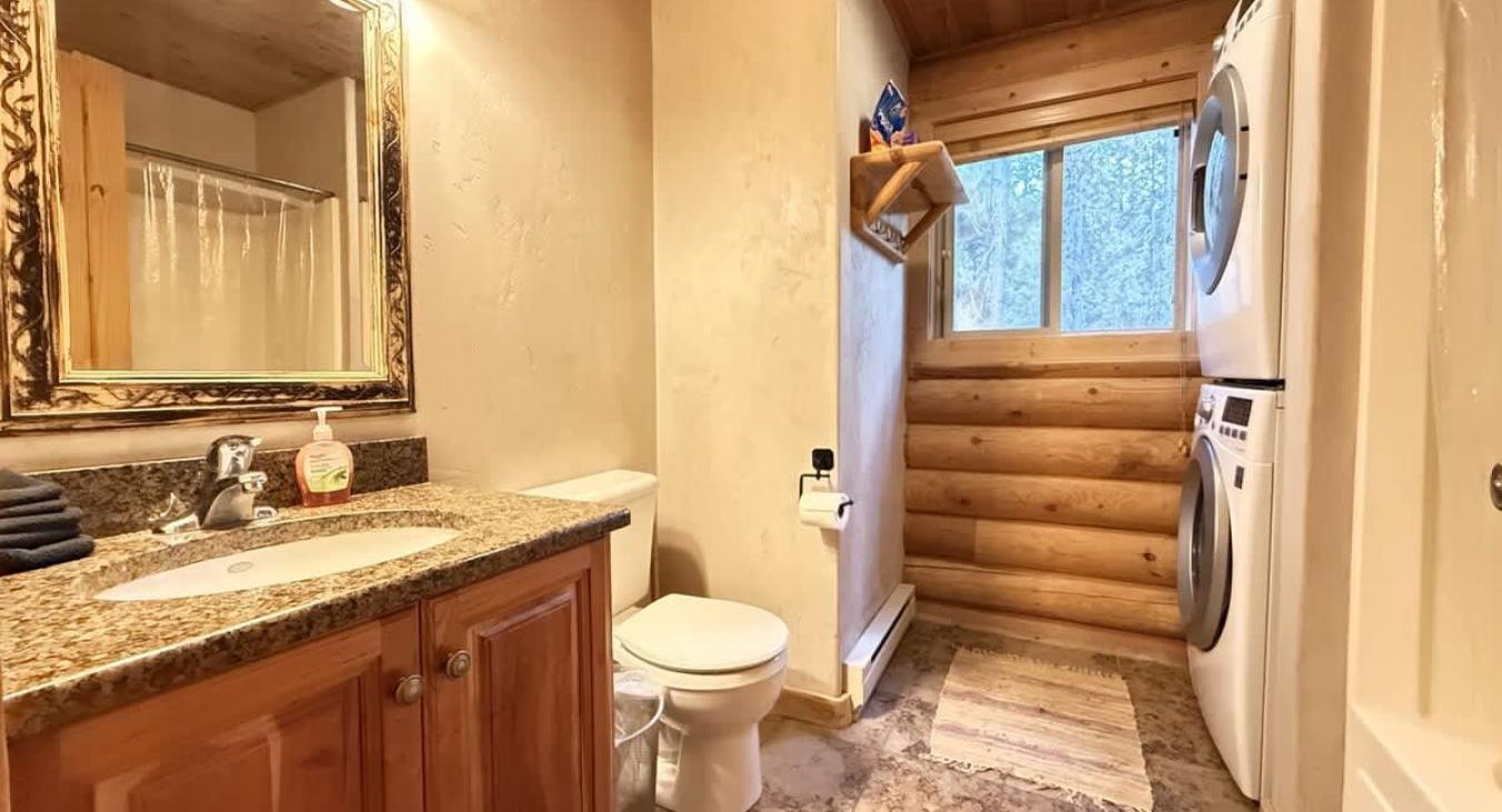 Main level bathroom with shower tub combo, toilet, and sink vantiy.