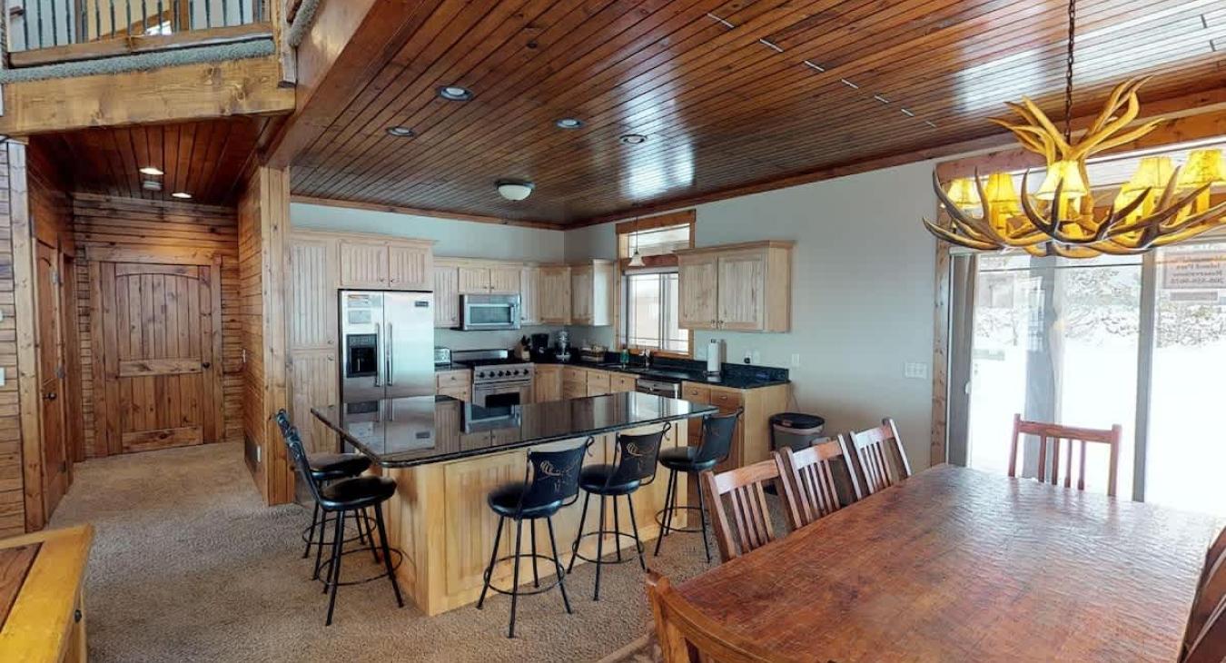 The dining room has a large table with seating and additional seating at the bar of the Island in the kitchen.