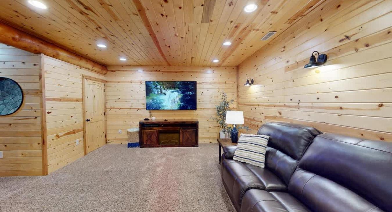 Along one wall, a large, plush couch is positioned facing the television, creating a perfect spot to unwind after a day of outdoor adventures or to catch a game or movie with friends.