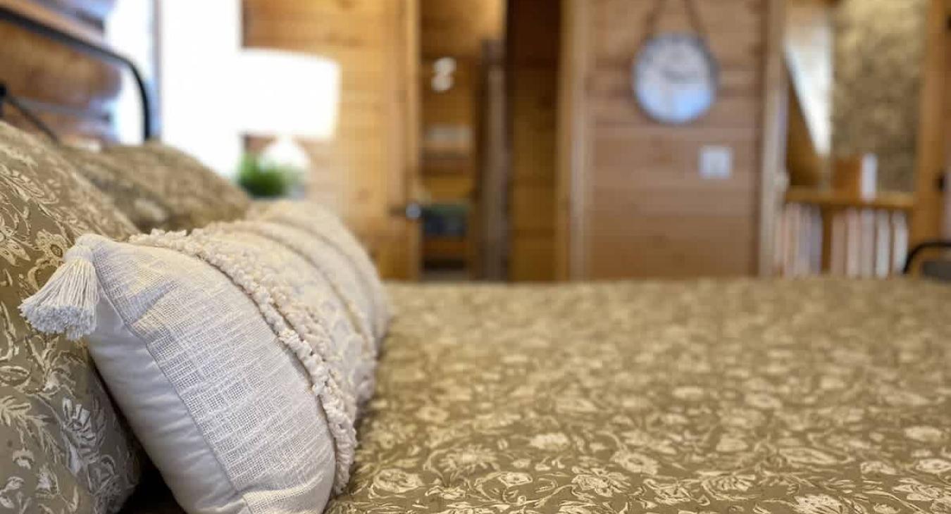 At the center of the room is a large, king-sized bed. The bed is positioned to offer a perfect view of the room and the stunning outdoor landscape just beyond.