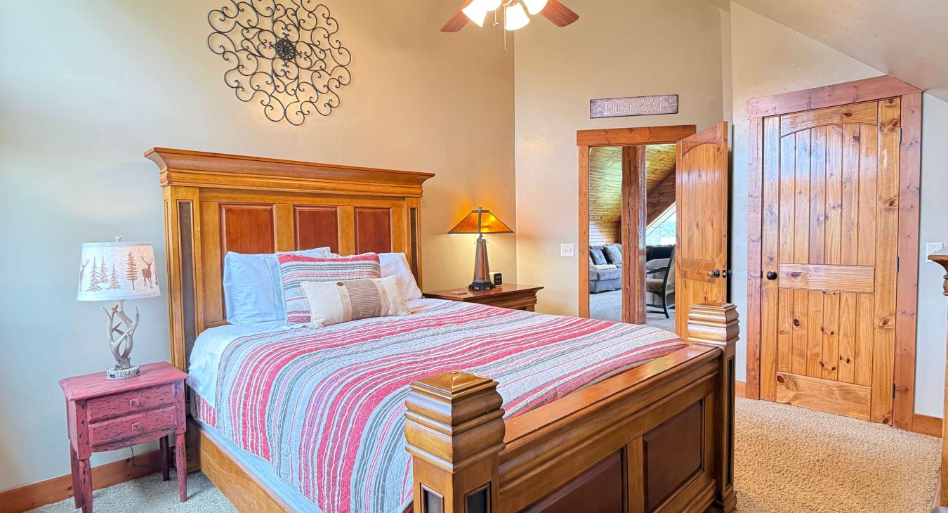 The second upstairs bedroom offers a warm, inviting atmosphere with a comfortable queen bed and high-quality wooden furnishings. There is also a closet to store your belongings during your stay.