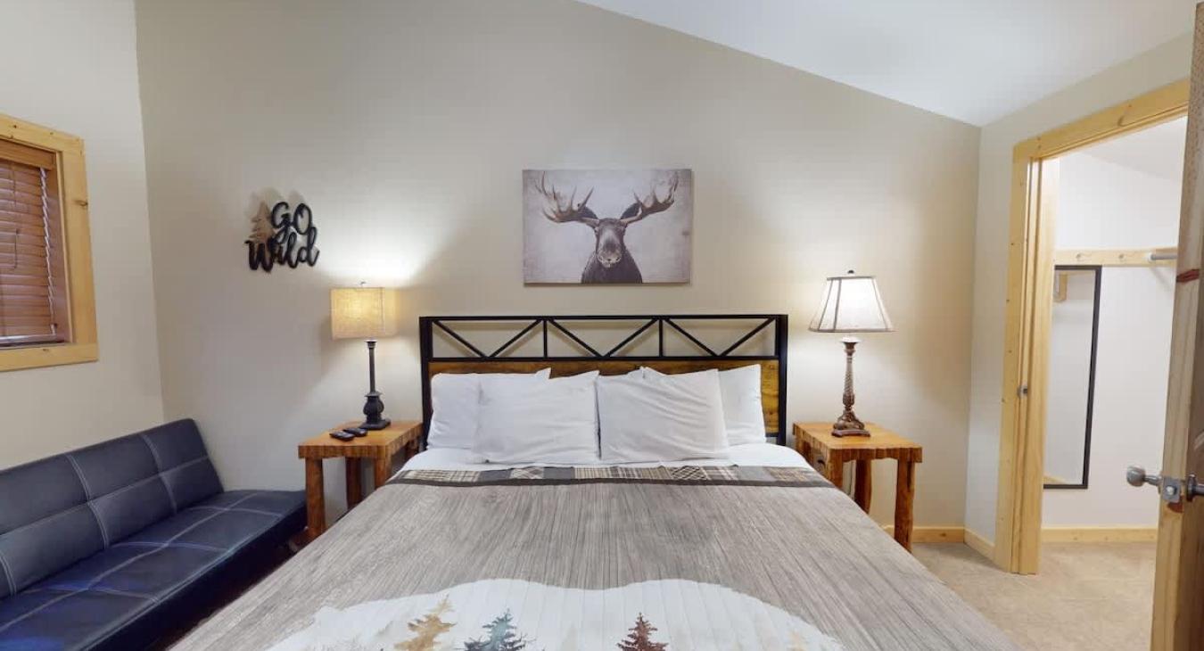 First bedroom with a king size bed, seating, and closet space.