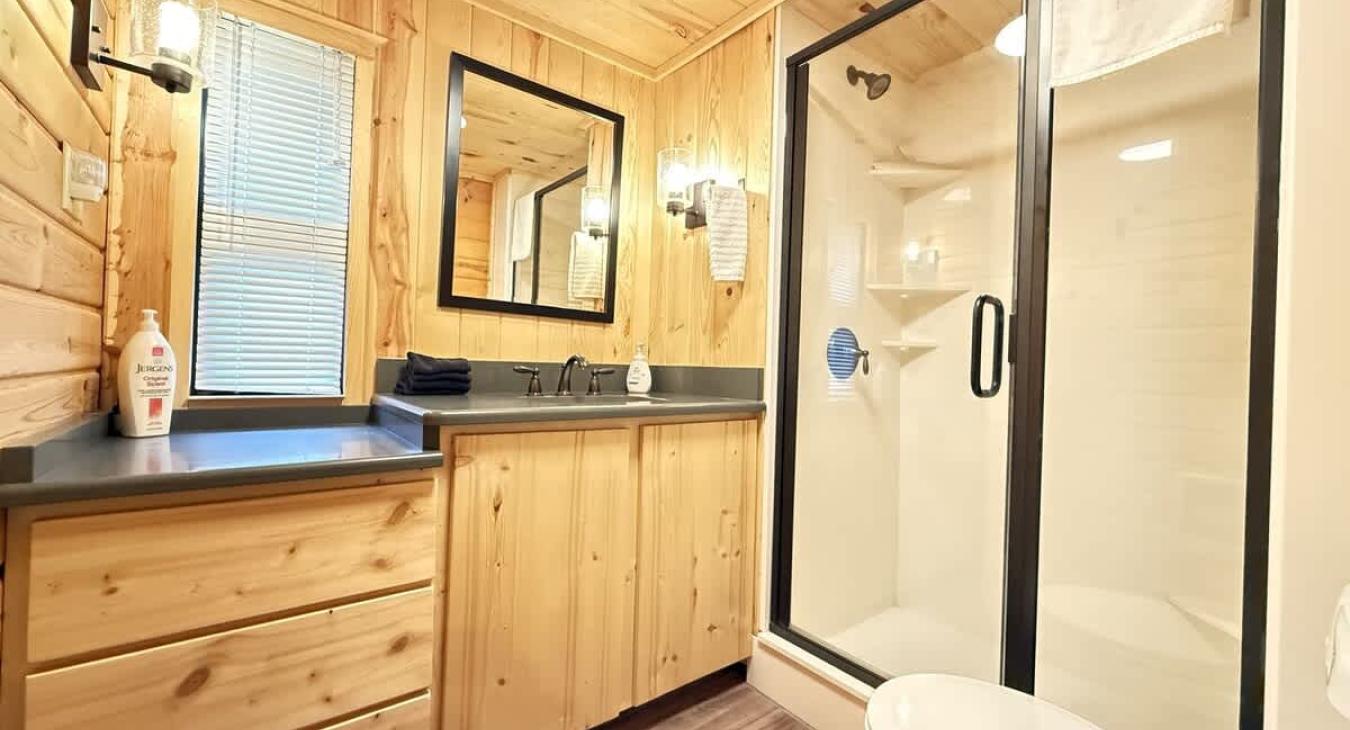 The bathroom is spacious and serene, blending the rustic elegance of the cabin with a touch of spa-like comfort.