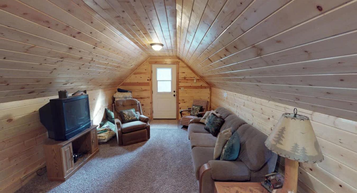 Garage upstairs sleeping area just a few steps from the main cabin. Living area is equipped with a tv and sofa.