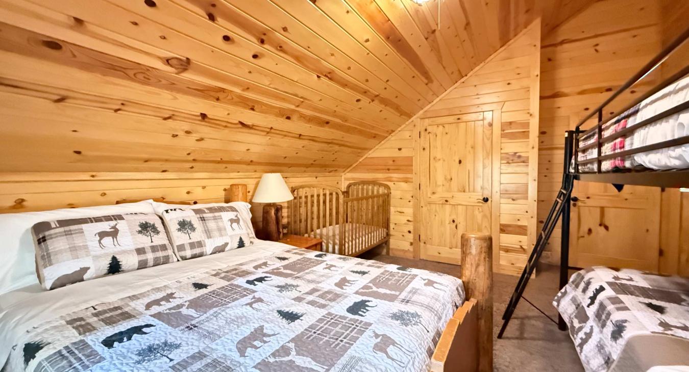 Ideal for guests with little ones, this warm upstairs room includes a comfortable Queen bed, a twin bunk bed, and a wooden baby crib.