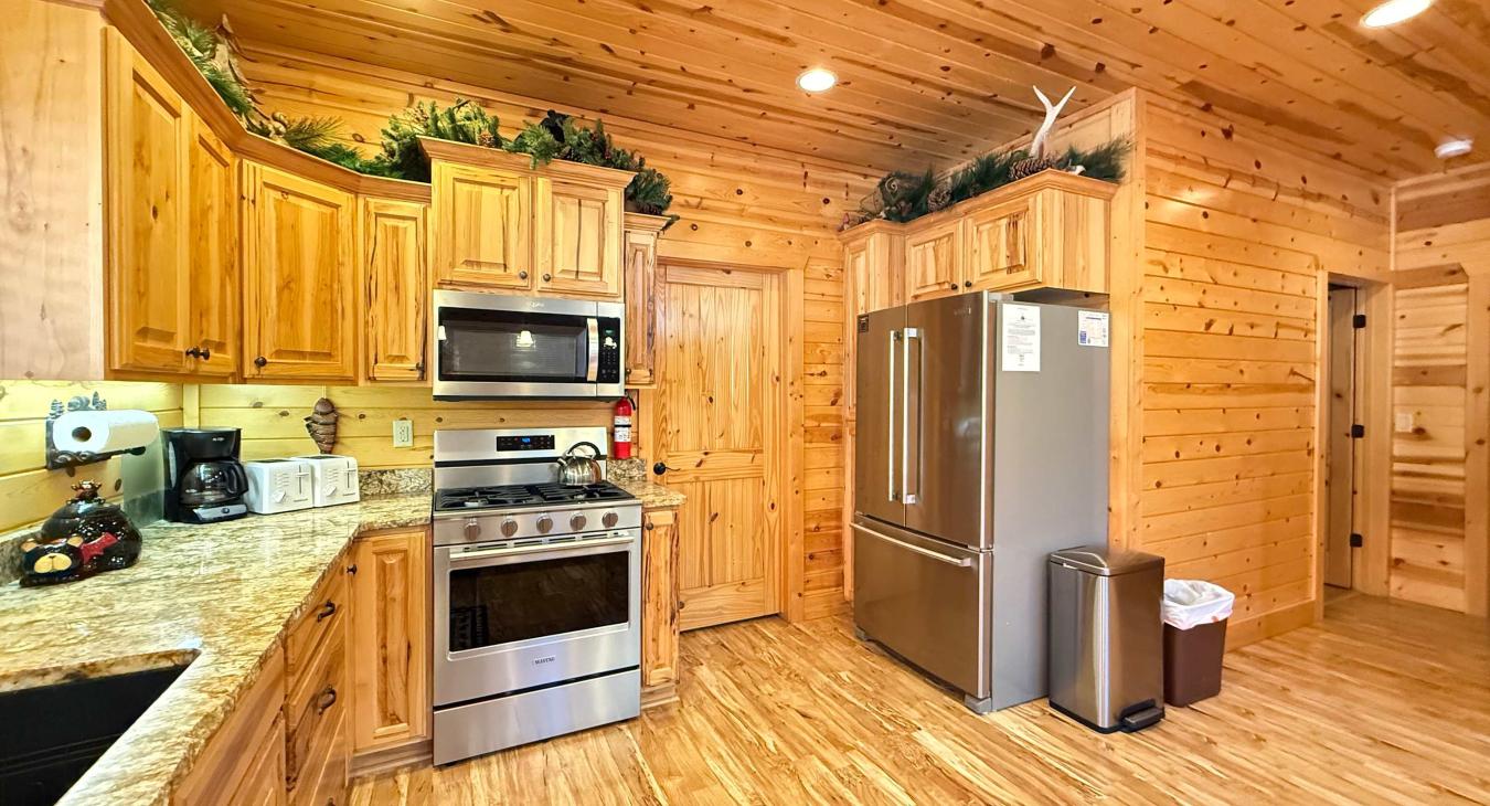 Enjoy modern cooking convenience surrounded by rich, authentic wood cabinetry and premium stainless steel appliances, including a spacious French-door fridge.