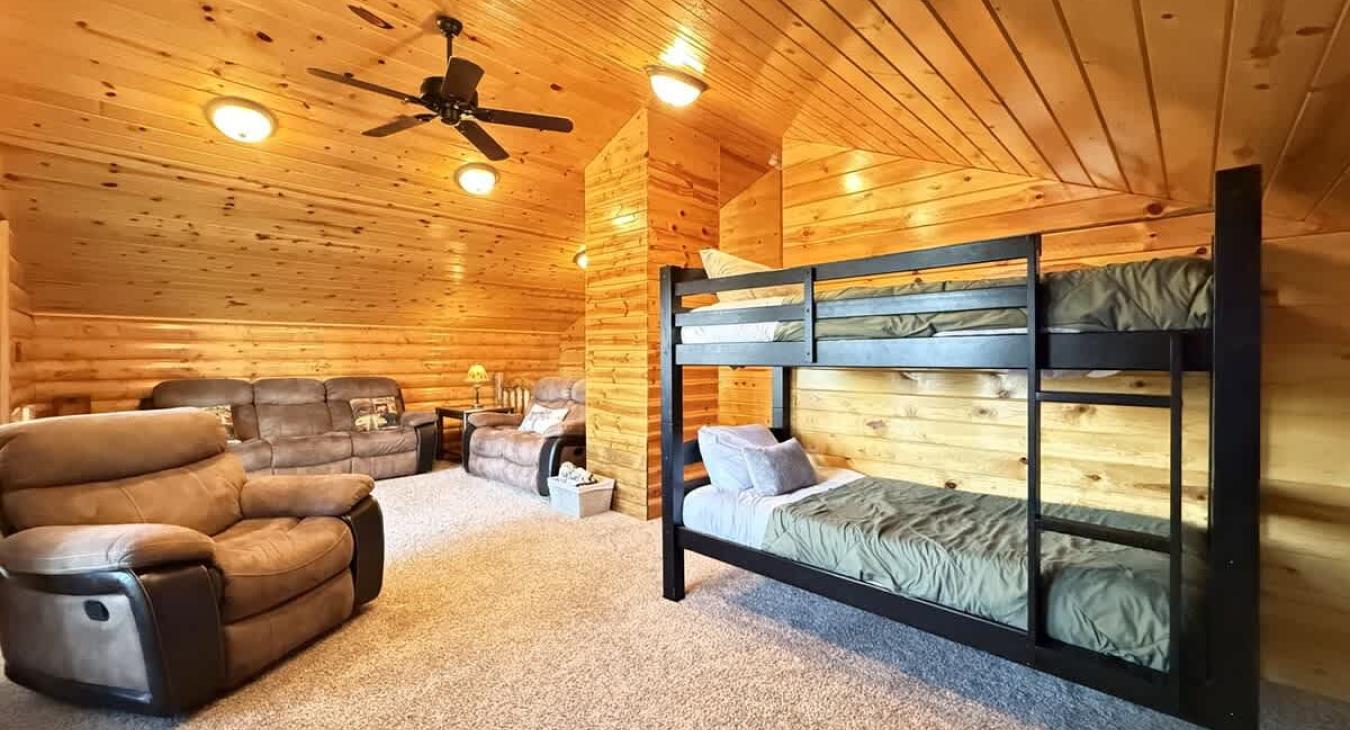 Upstairs loft with a single on single bunk bed with a smart tv and electric fireplace along with seating.