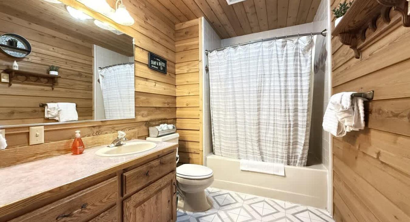 Full size bathroom with a tub shower combo, toilet, and sink.
