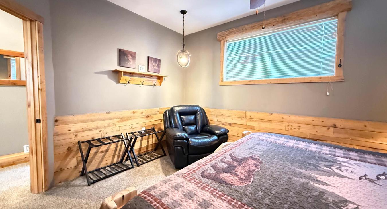 The charming Queen room offers ample space, complete with luggage racks, cozy log accents, and easy access to the hallway.
